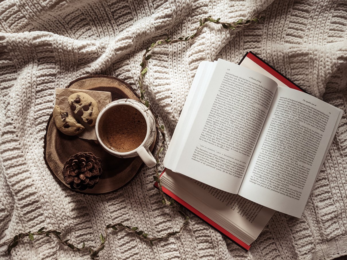 White Ceramic Mug Beside an Open Book